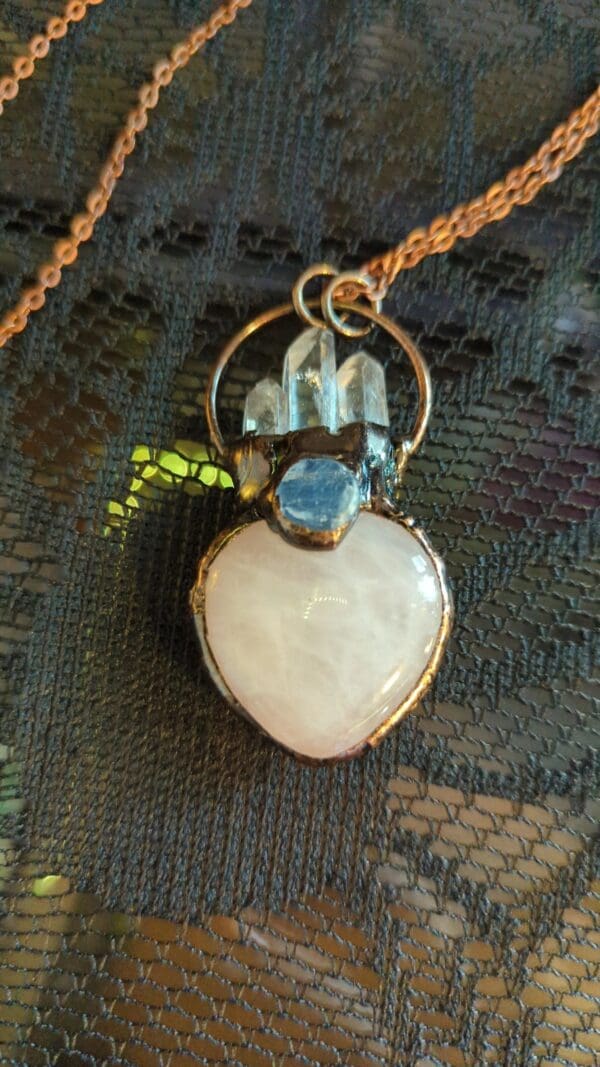 A necklace with a heart shaped stone and some kind of crystal.