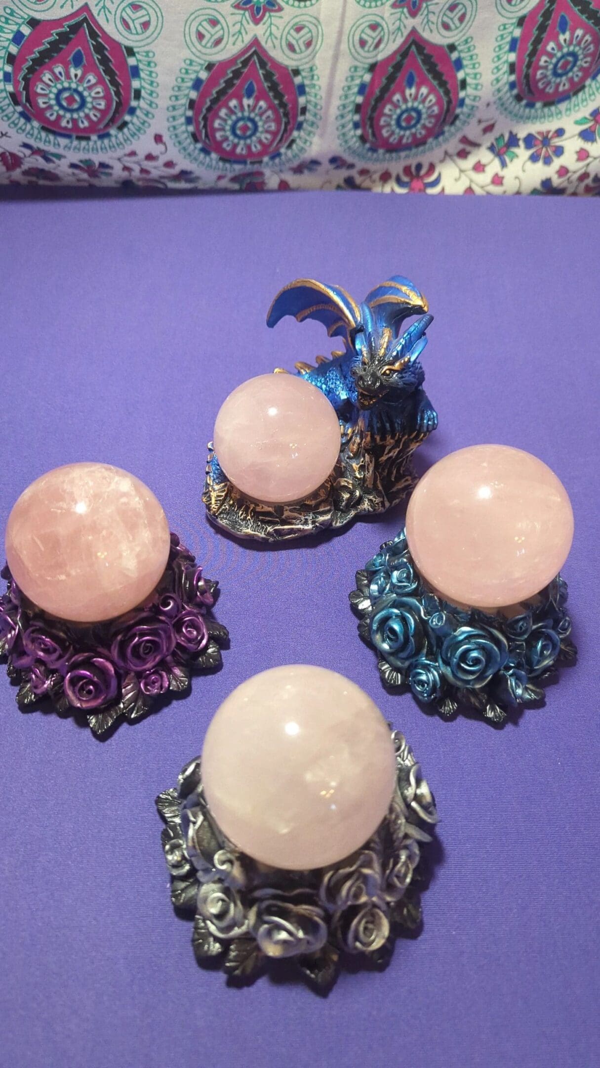 A purple table with three different colored stands and four crystal balls.