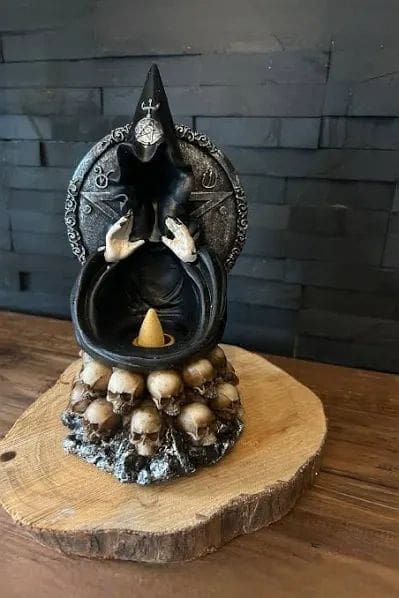 A statue of a witch with skulls on top.