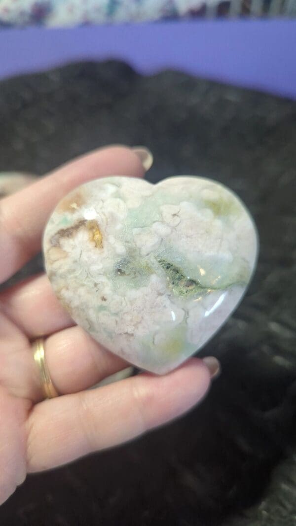 A person holding a heart shaped stone in their hand.